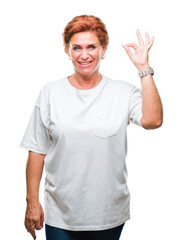 Wall Mural - Atrractive senior caucasian redhead woman over isolated background smiling positive doing ok sign with hand and fingers. Successful expression.