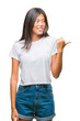 © Krakenimages.com - Young asian woman over isolated background smiling with happy face looking and pointing to the side with thumb up.