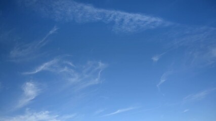 Wall Mural - time lapse of a few wispy white clouds moving across a bright blue sky