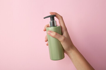 Canvas Print - Woman with shampoo bottle on pink background, closeup