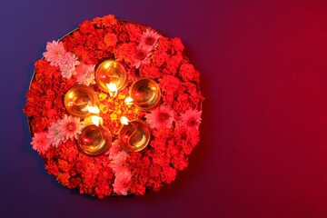 Canvas Print - Diwali celebration. Diya lamps and beautiful flowers on color background, top view. Space for text