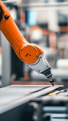 Poster - An orange robotic arm with a white end effector is shown in close up as it reaches down to an assembly line.