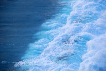 Turquoise ocean sea water white wave pattern splashing deep blue sea. Seascape dark ocean background wave splash on rock. Tropical sea beach in summer seaside outdoor. Water Surface blue wave pattern