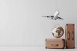 © Kdhtdg - 3D render of a travel concept with a globe, airplane, and suitcases on a white background.