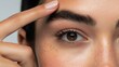 © Oulaphone - A close-up of a person's eye and brow, showcasing detailed skin texture and a finger gently resting on the brow.