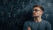 © tinnakorn - A pensive man in glasses contemplates against a chalkboard marked with question marks, symbolizing curiosity and uncertainty.