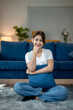 © Wasana - A woman is sitting on the floor with a blue pillow on her lap
