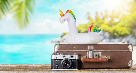 Fototapete - A bag with travel stuff, camera, and floating flamingo placed on a table