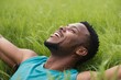 © Introvertia - Smiling African American man lying in field of green grass