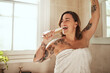 © Malambo/peopleimages.com - Woman, happy and brush in bathroom for singing, morning routine and excited for self care with towel. Female person, smile and dance in home for personal hygiene, grooming and weekend with tattoo