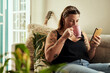 © Malambo/peopleimages.com - House, coffee and woman on sofa, cellphone and internet with social media, texting and connection. Herbal tea, person and girl on couch, smartphone and typing with message to contact and cappuccino