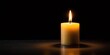 © yuwaree - Partly visible lighted candle in front of black background symmetrical