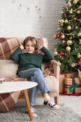 Wall Mural - Cute little boy in headphones sitting at home on Christmas eve