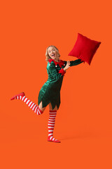 Poster - Happy young woman dressed as elf with pillow on orange background