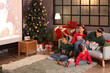 © Pixel-Shot - Happy family watching Christmas movie on projector screen at home