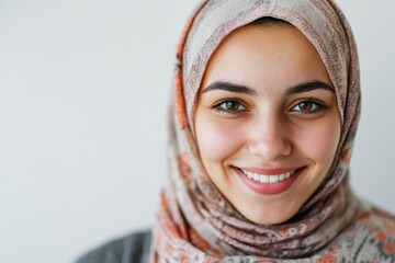 Muslim woman smiling, reflecting warmth and positivity on solid white background,