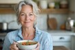 © Gema Vélez - Mature woman eating a bowl of soup in the kitchen of her home.