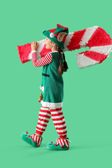 Canvas Print - Cute little elf with candy cane pinata walking on green background