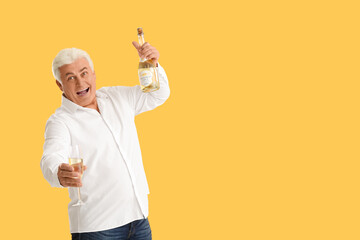 Wall Mural - Happy senior man with bottle and glass of champagne celebrating Christmas on orange background