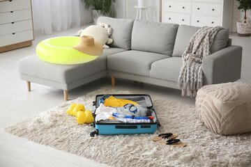 Wall Mural - Packed suitcase with clothes, beach accessories and inflatable ring in living room. Summer vacation concept