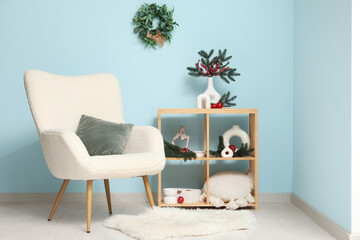 Wall Mural - Interior of living room with armchair, shelving unit and Christmas decor near blue wall