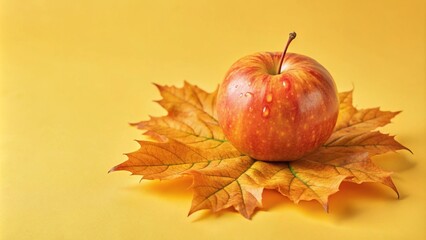 Wall Mural - Red apple with water drops on a yellow leaf with a yellow background.