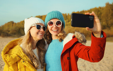 Wall Mural - Happy young two women friends taking selfie with phone on beach, smiling girlfriends having fun