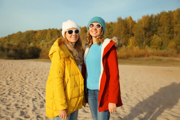 Wall Mural - Happy young two women friends on sunny beach, stylish girlfriends smiles together on sea coast