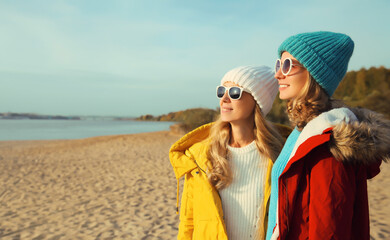 Wall Mural - Happy young two women friends on sunny beach, stylish girlfriends smiles together on sea coast