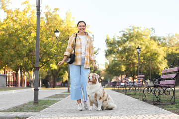 Poster - Young woman with Australian Shepherd dog walking in park