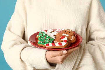 Wall Mural - Young woman with tasty Christmas gingerbread cookies on blue background, closeup