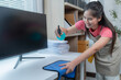 © Tj - Cheerful woman cleans an office desk with a blue rag and spray bottle, ensuring hygiene and organization
