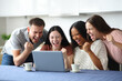 © Antonioguillem - Four euphoric roommates celebrating checking laptop