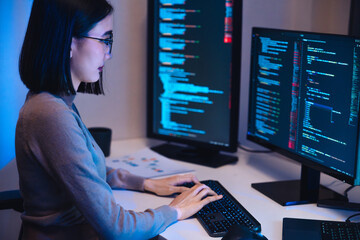 Wall Mural - asian woman software development working on coding computer screen and flowchart at night in modern 