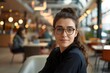 © Татьяна Евдокимова - Portrait of a young businesswoman wearing glasses sitting in a coworking space with a confident smile
