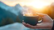 © tuiphotoengineer - Close up view of hands holding a warm steaming coffee cup placed on a windowsill with a scenic mountain silhouette visible through the glass and soft morning light filtering in