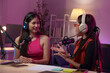 © crizzystudio - Two beautiful women chat while co-hosting an audio broadcast in a home studio. Recording internet podcasts for social media channels Ideas for creating online work.