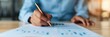 © Vilaysack - Close-up of a person writing on a document at a desk, focusing on hand holding a pencil, representing business and analysis concept.