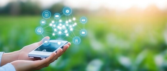 A hand holding a smartphone with digital icons over a green field, representing connectivity and technology in agriculture.