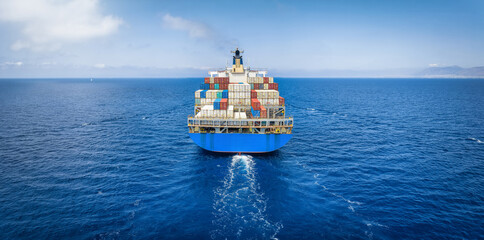 Rear view of a large container cargo ship traveling over the ocean with copy space