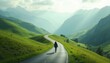 © natakot - A scenic view of a man walking alone on a winding road through green mountains under a cloudy sky.