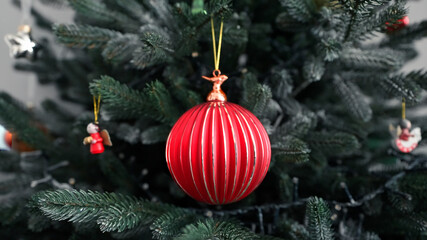 Wall Mural - Christmas concept tree decorative red glass retro ball rotate on branch close up on back ground bokeh of side flickering light bulbs garlands winter family holiday. Happy New Year Festival mood. Noel