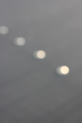 Wall Mural - a blurry dreamy view of white lights shining on the gray background.