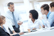 © STEEXBuyout/peopleimages.com - Businessman, documents and discussion with team for meeting, corporate plan or project at office. Man, executive or speaker talking to group of employees for business improvement or development