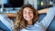 © Pinklife - A content woman leans back with a big smile on a cozy couch, embodying relaxation and peace in a modern living space, highlighting joy and comfort.