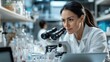 © Pinklife - A woman in a lab coat is deeply focused on her work with a microscope in a modern laboratory, showcasing dedication and precision in scientific research.