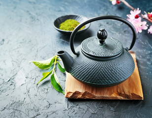 Traditional Japanese teapot for brewing tea with green tea on grey background