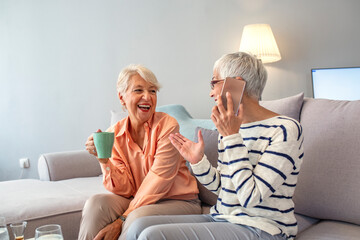 Happy Senior Women Laughing Together on a Comfortable Sofa