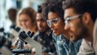 © irawan - A group of students wearing safety glasses focus intently on a microscope in a science laboratory.