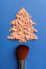 Sticker - Christmas tree made with face powder and brush on blue background, top view